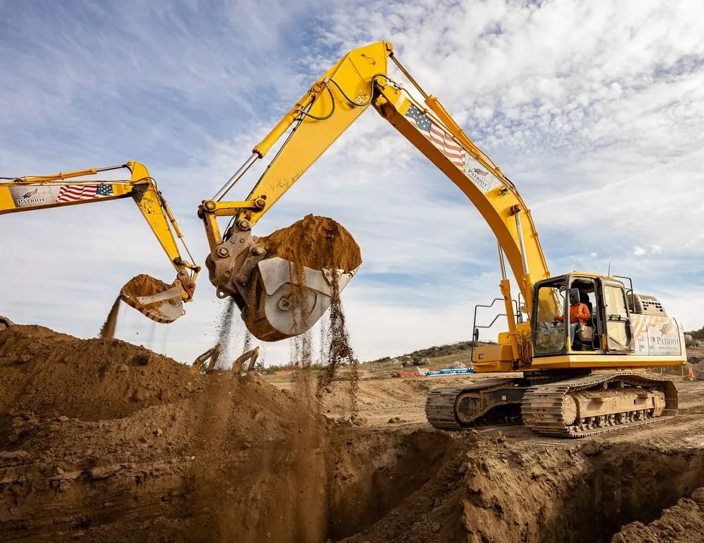 Excavators trenching for wet utility pipeline installation